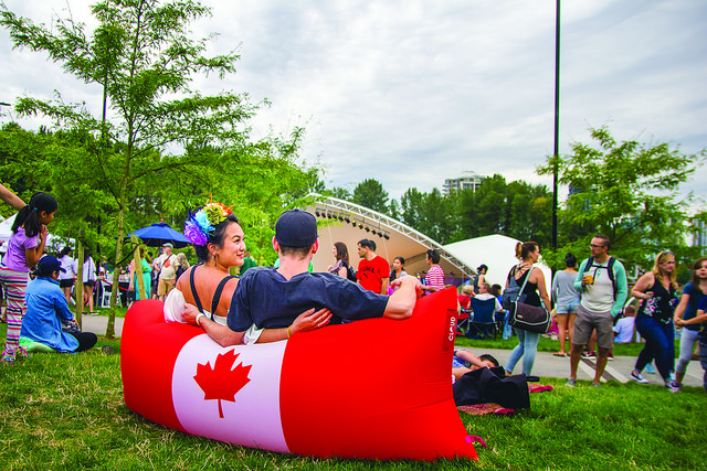 Coquitlam Canada Day - Town Centre Park Two People Sitting on an Inflatable Pillow Chair Featuring the Canada Flag