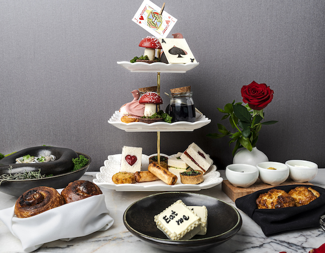 Extravagant Alice + Wonderland themed tea display with cake and a tower of cards and pastries