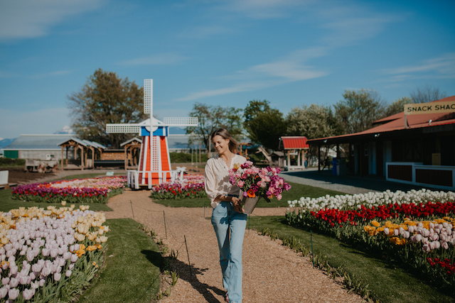 Woman picking flowers at Greendale Acres for Mother's Day by windmill