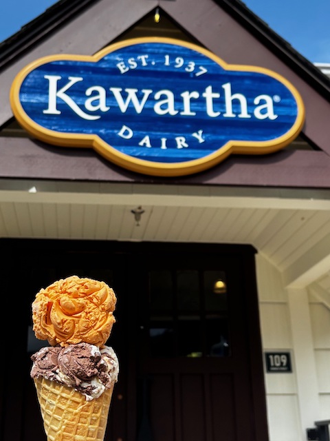 Ice cream cone being held in front of Kawartha Dairy Britannia Village Building