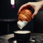 Croissant being dunked into a latte from Dolce Cafe